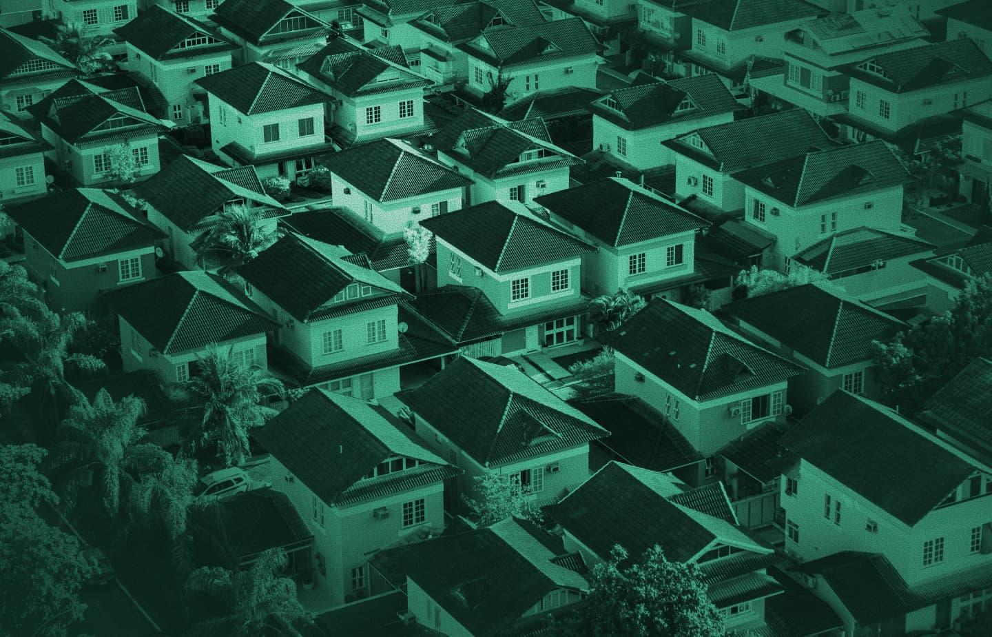 Aerial view of dense suburban houses and rooftops, green monochrome tint