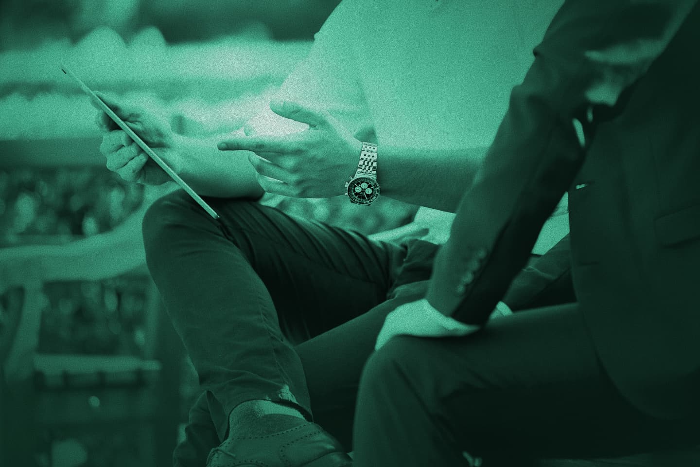 Two professionals reviewing a tablet outdoors on a bench, green-tinted photo