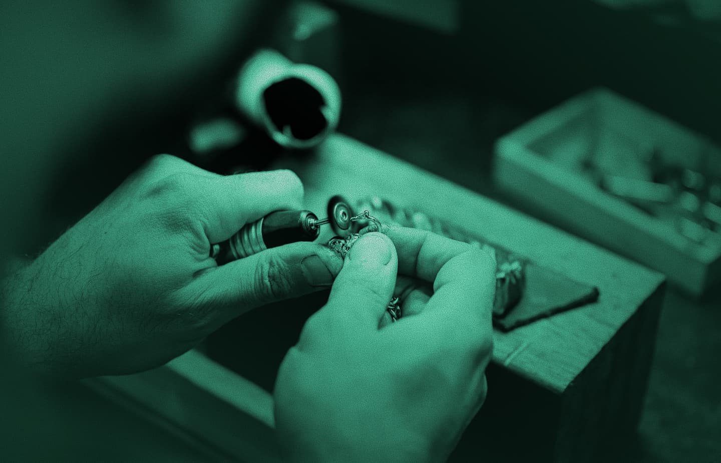 Close-up of a jeweller’s hands polishing a small metal piece with a rotary tool