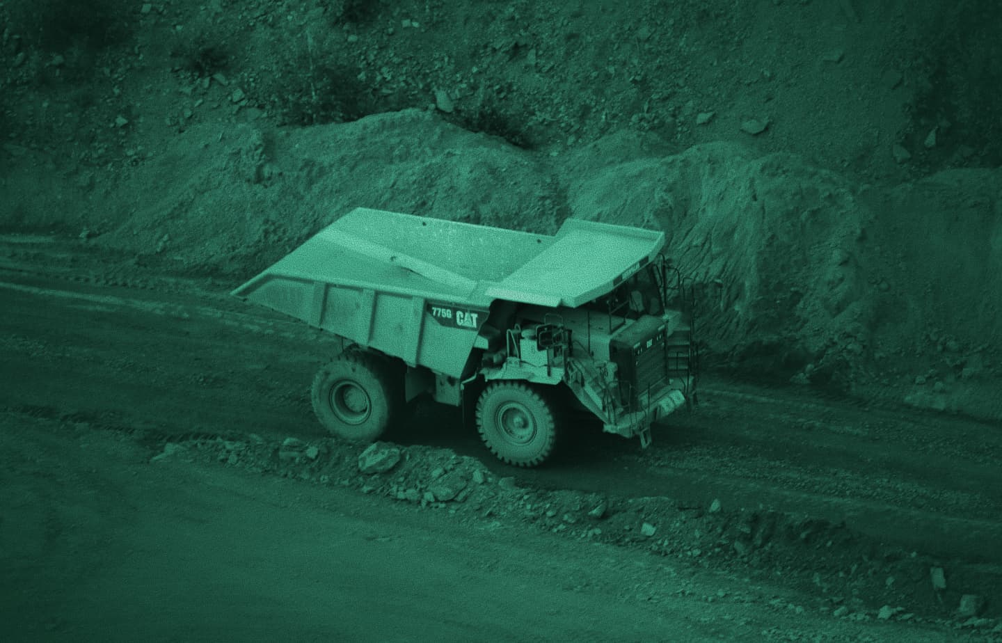 Caterpillar 775G haul truck on a dirt road in a quarry, green-tinted photo