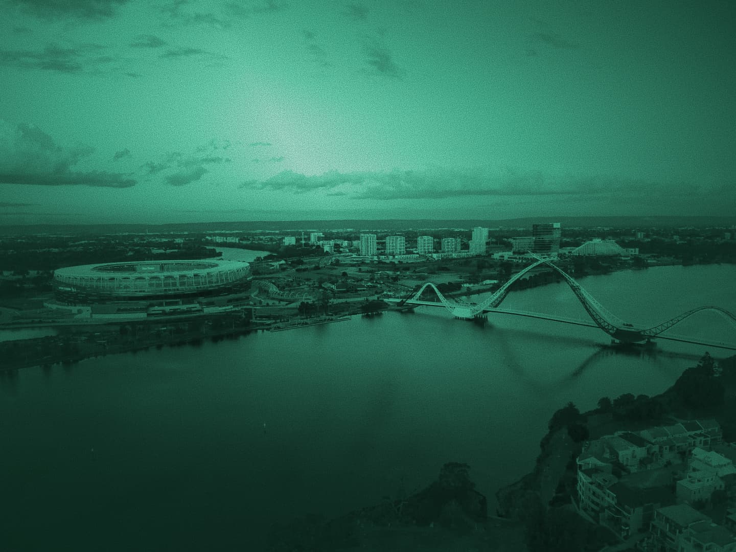 Aerial dusk view of Optus Stadium and Matagarup Bridge over the Swan River in Perth