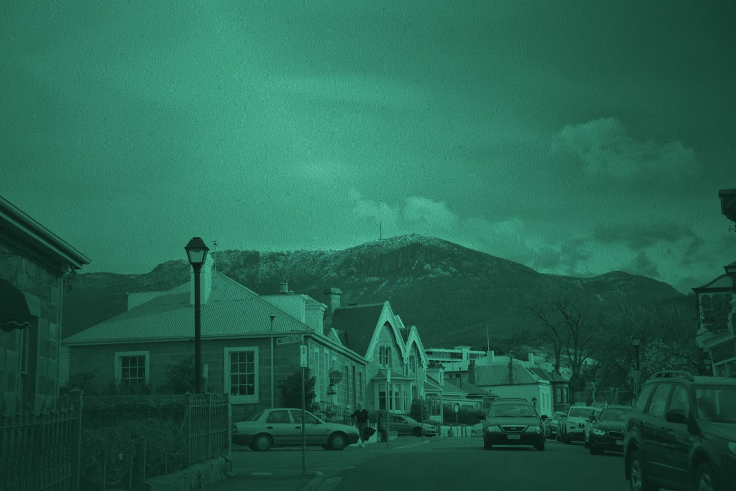 Hobart street lined with stone houses leading toward snow-dusted kunanyi / Mount Wellington